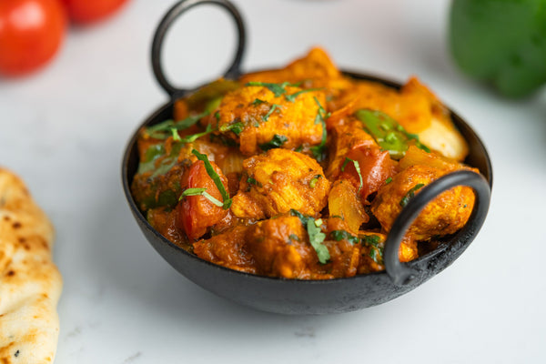 Chicken karahi, a peppery chicken curry with tomato, onion and green pepper, served in a karahi dish with naan