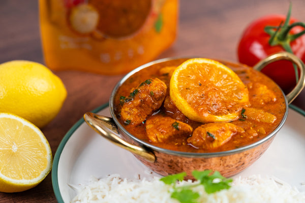 Chicken sambar, a hot and tangy chicken curry made with Dhansak sauce, topped with a lemon slice and served with rice